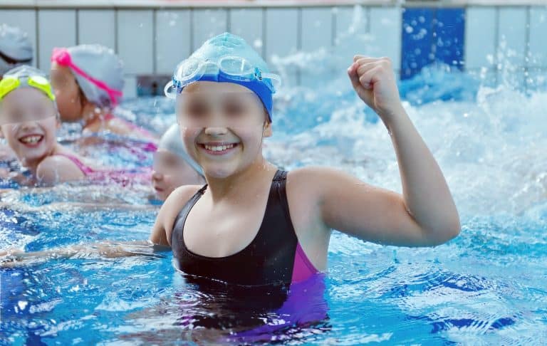 Happy children kids group at swimming pool class learning to swim